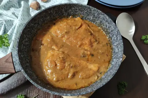 Bitki z indyka w sosie własnym, gotowe do podania. Aromatyczne danie w patelni, ozdobione natką pietruszki.