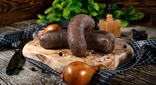 Kaszanka na desce, cebula, przyprawy. Zastanawiasz się, jak długo można przechowywać kaszankę w lodówce?