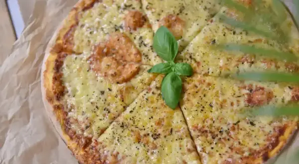 Pyszna pizza z rozpływającym się serem, ozdobiona listkiem bazylii. Idealny ser do pizzy, który zachwyca smakiem.