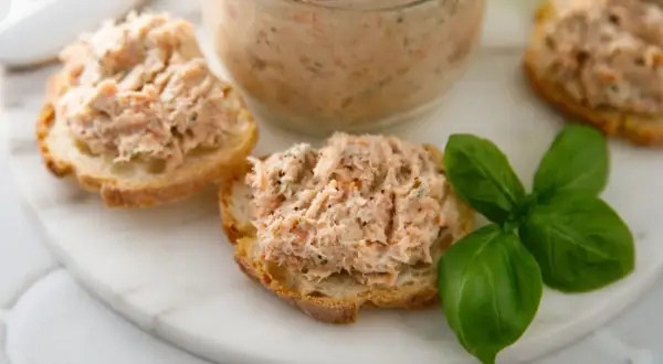 Pyszna pasta rybna na chrupiących grzankach, ozdobiona listkami bazylii. Idealna na szybką przekąskę.