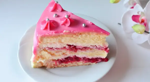 Pyszny kawałek tortu z warstwami biszkoptu, kremu i malinową frużeliną. Wierzch udekorowany różowym lukrem i srebrnymi perełkami. Idealny krem malinowy z mascarpone do tortu.