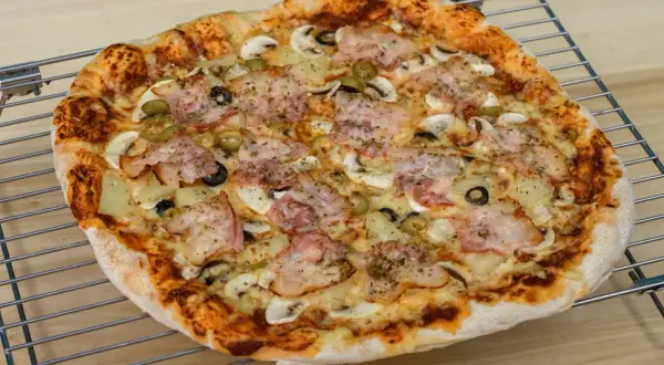 Pyszna pizza z szynką, pieczarkami, oliwkami i ananasem. Idealna na rodzinny obiad, zastanawiasz się ile piec pizze?