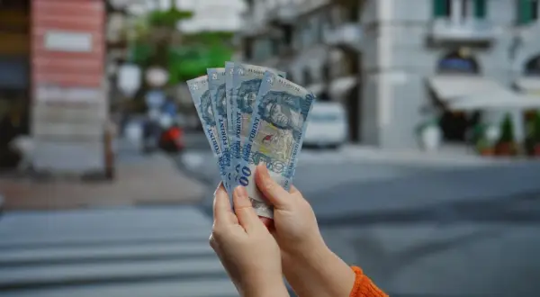 Ręce trzymają pięć banknotów po 1000 forintów. Tyle forintów kosztuje obiad na Węgrzech?