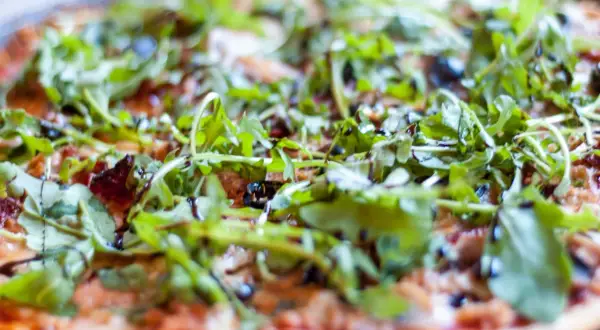 Pyszna pizza z tuńczykiem, rukolą i oliwkami, polana sosem balsamicznym. Idealna na szybki obiad.