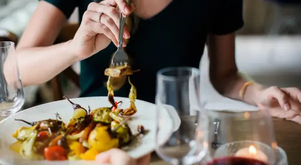 Kobieta je warzywa z grilla, zastanawiając się, ile kcal na obiad.