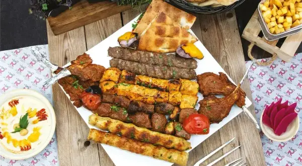 Nietypowe dania z grilla: bogactwo mięs, warzyw i pieczywa na talerzu.