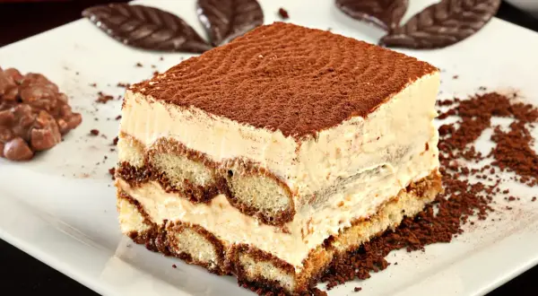 Pyszne tiramisu, idealne na prosty przepis na ciasto cappuccino. Warstwy biszkoptów i kremu, posypane kakao.