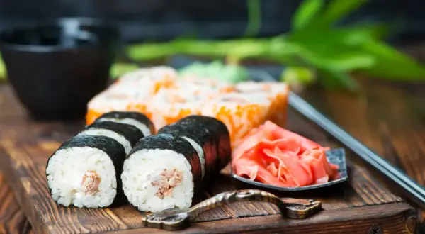 Pyszne sushi z kremowym nadzieniem, obok marynowany imbir i miseczka na sos do sushi.
