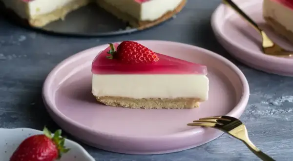 Pyszny deser z mascarpone i galaretką, udekorowany truskawką, czeka na talerzyku.