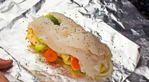 Ryba z piekarnika z warzywami: soczysty filet rybny owinięty w folię aluminiową z marchewką, cukinią i brokułami.