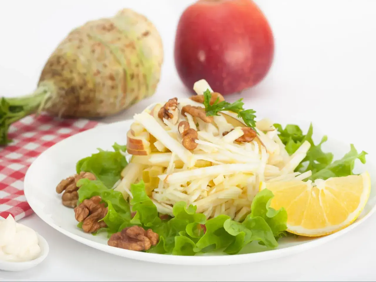 Wykwintna surówka z selera jak w restauracji, z jabłkiem, orzechami i cytryną, na tle selera i jabłka.