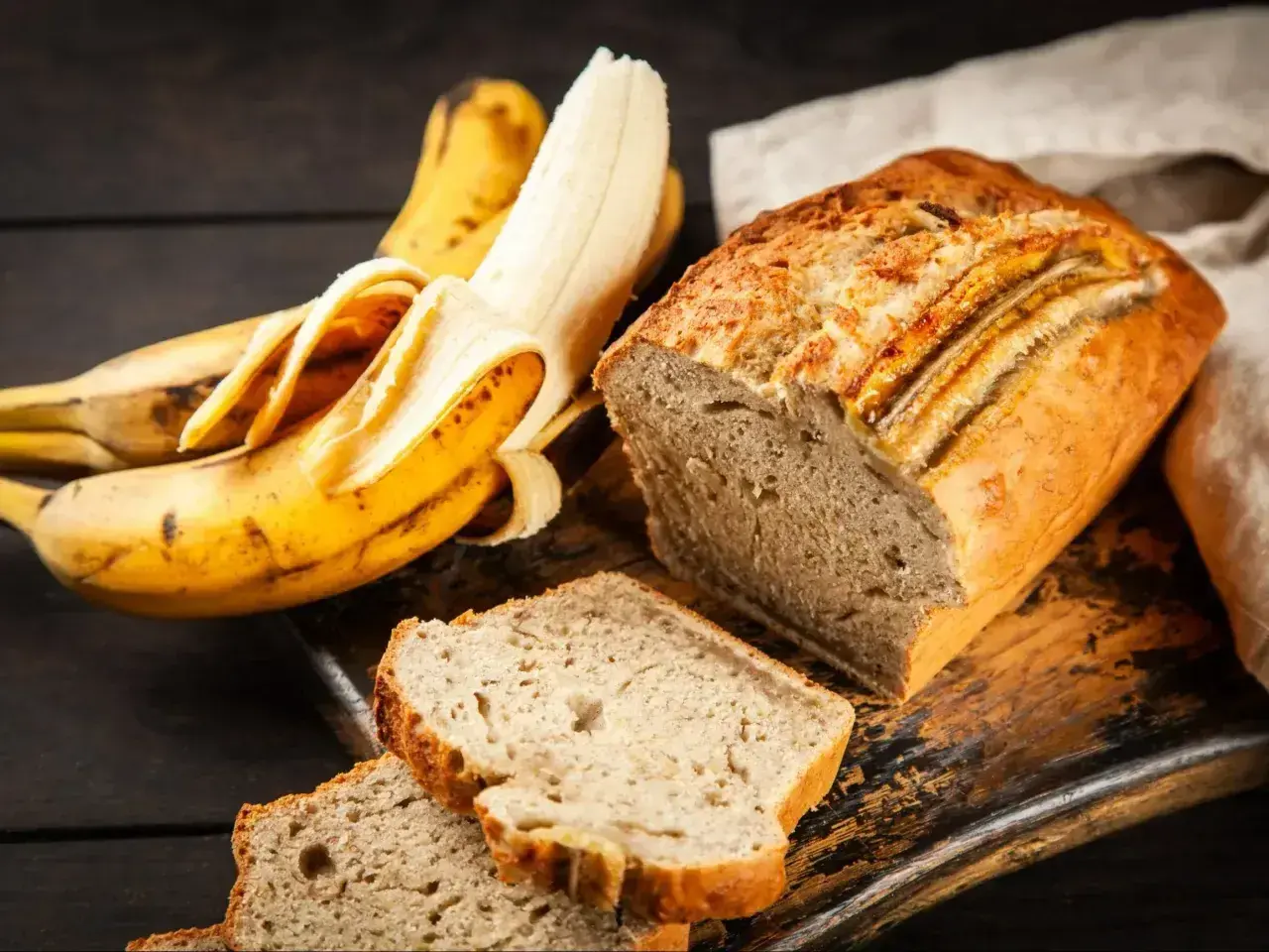 Wilgotne ciasto bananowe, pachnące i pyszne, obok dojrzałych bananów. Idealne na deser lub śniadanie.