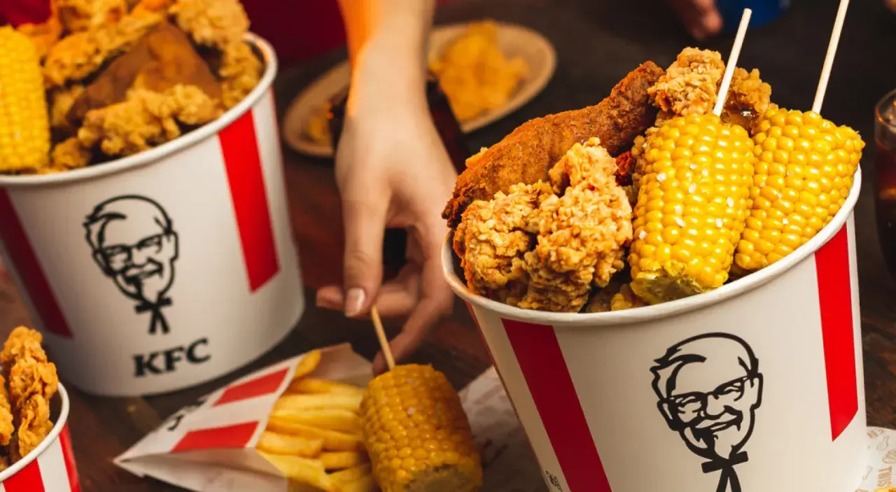 Kukurydza w KFC ma najmniej kalorii. Na zdjęciu kubełki z kurczakiem, frytki i kolby kukurydzy.