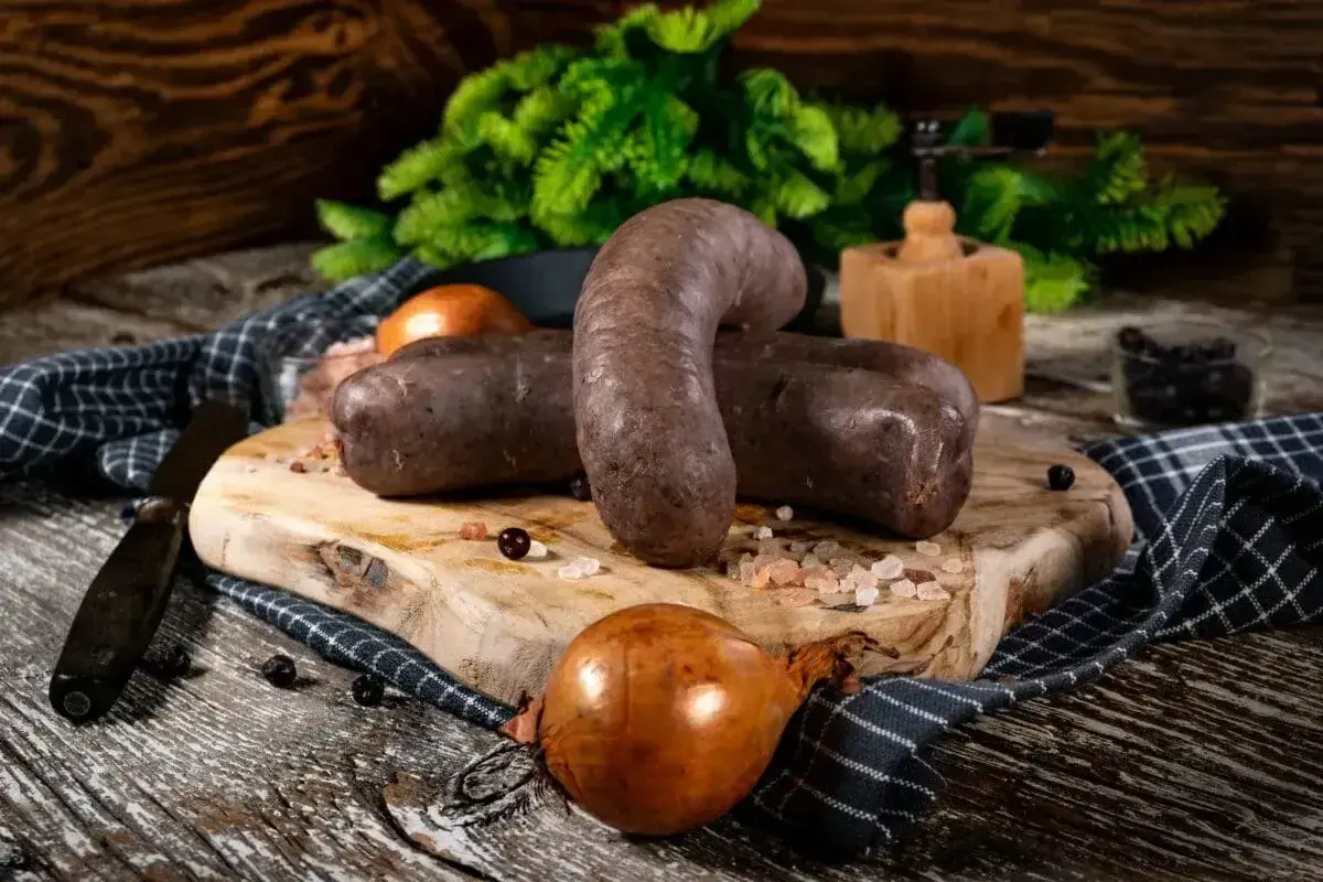 Kaszanka na desce, cebula, przyprawy. Zastanawiasz się, jak długo można przechowywać kaszankę w lodówce?