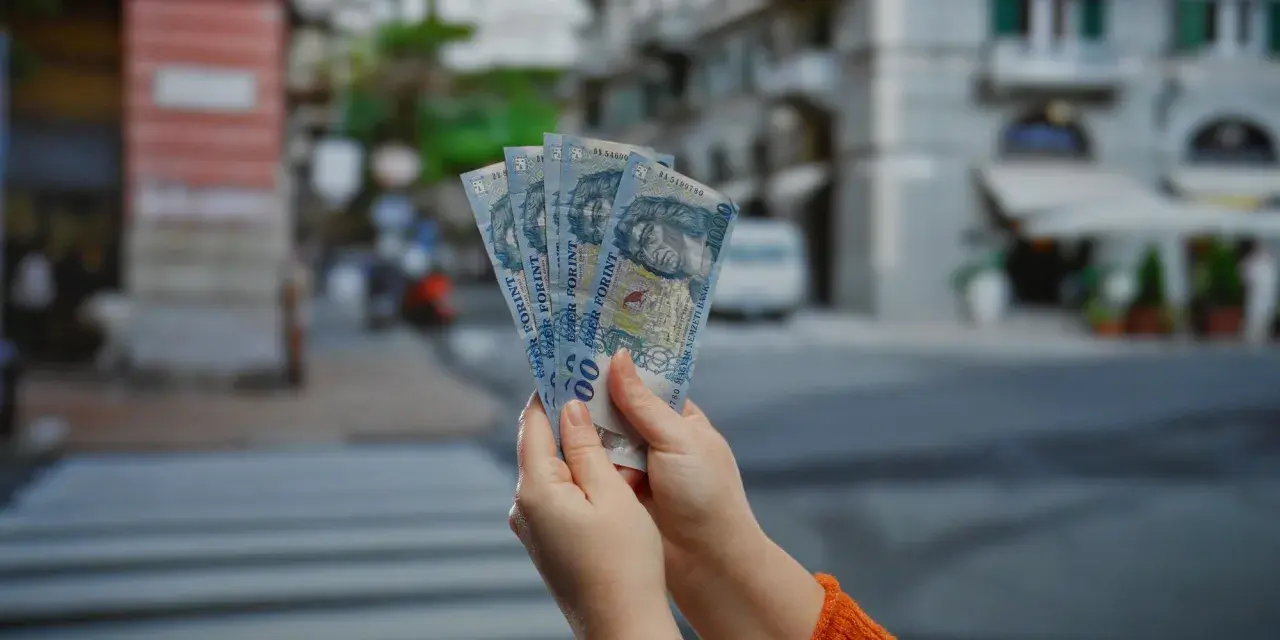 Ręce trzymają pięć banknotów po 1000 forintów. Tyle forintów kosztuje obiad na Węgrzech?