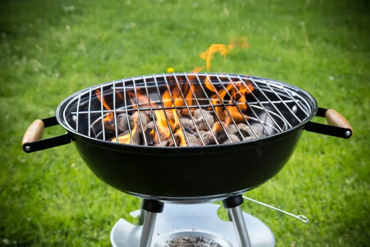 Rozpalony grill węglowy z płomieniami, gotowy do grillowania. Idealny przykład, jak rozpalic grilla na letnie popołudnie.