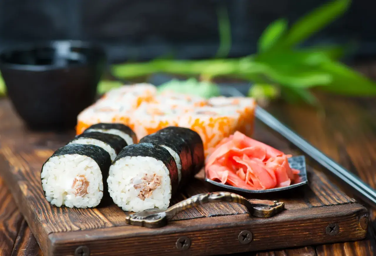 Pyszne sushi z kremowym nadzieniem, obok marynowany imbir i miseczka na sos do sushi.