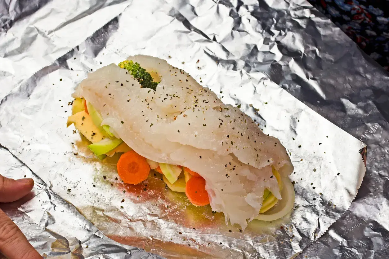 Ryba z piekarnika z warzywami: soczysty filet rybny owinięty w folię aluminiową z marchewką, cukinią i brokułami.