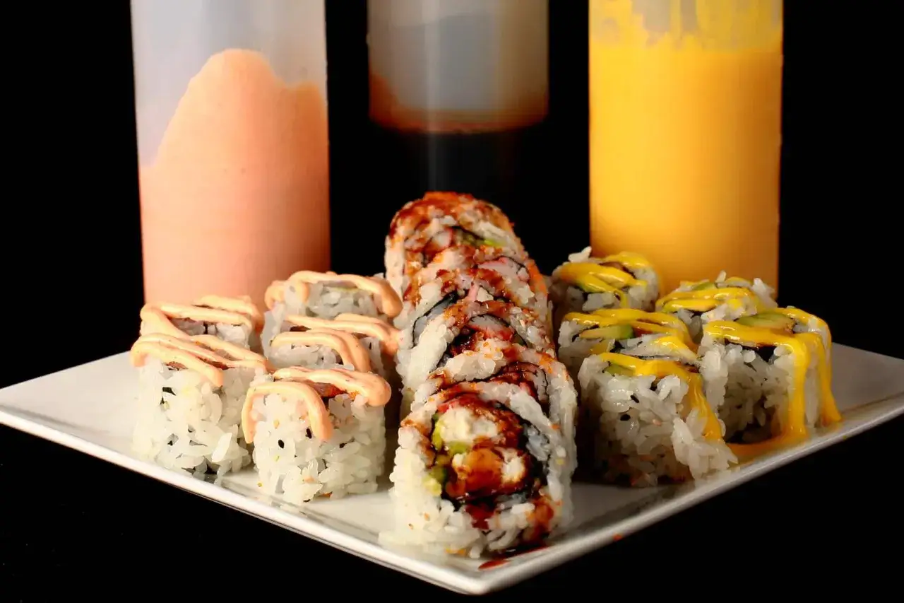 Talerz sushi z trzema sosami: różowym, pomarańczowym i żółtym. Idealny sos do sushi dla każdego smaku.