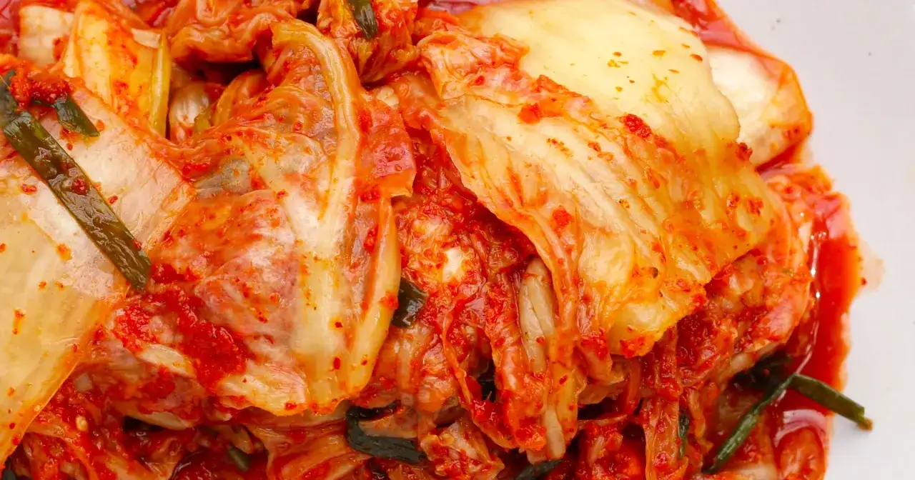 Pikantne, fermentowane warzywa, czyli co to jest kimchi. Liście kapusty pekińskiej pokryte czerwoną pastą chili i kawałkami zielonej cebulki.
