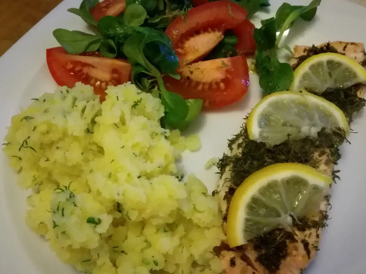 Pyszny łosoś z grilla, podany z puree ziemniaczanym z koperkiem i świeżą sałatką z pomidorów.