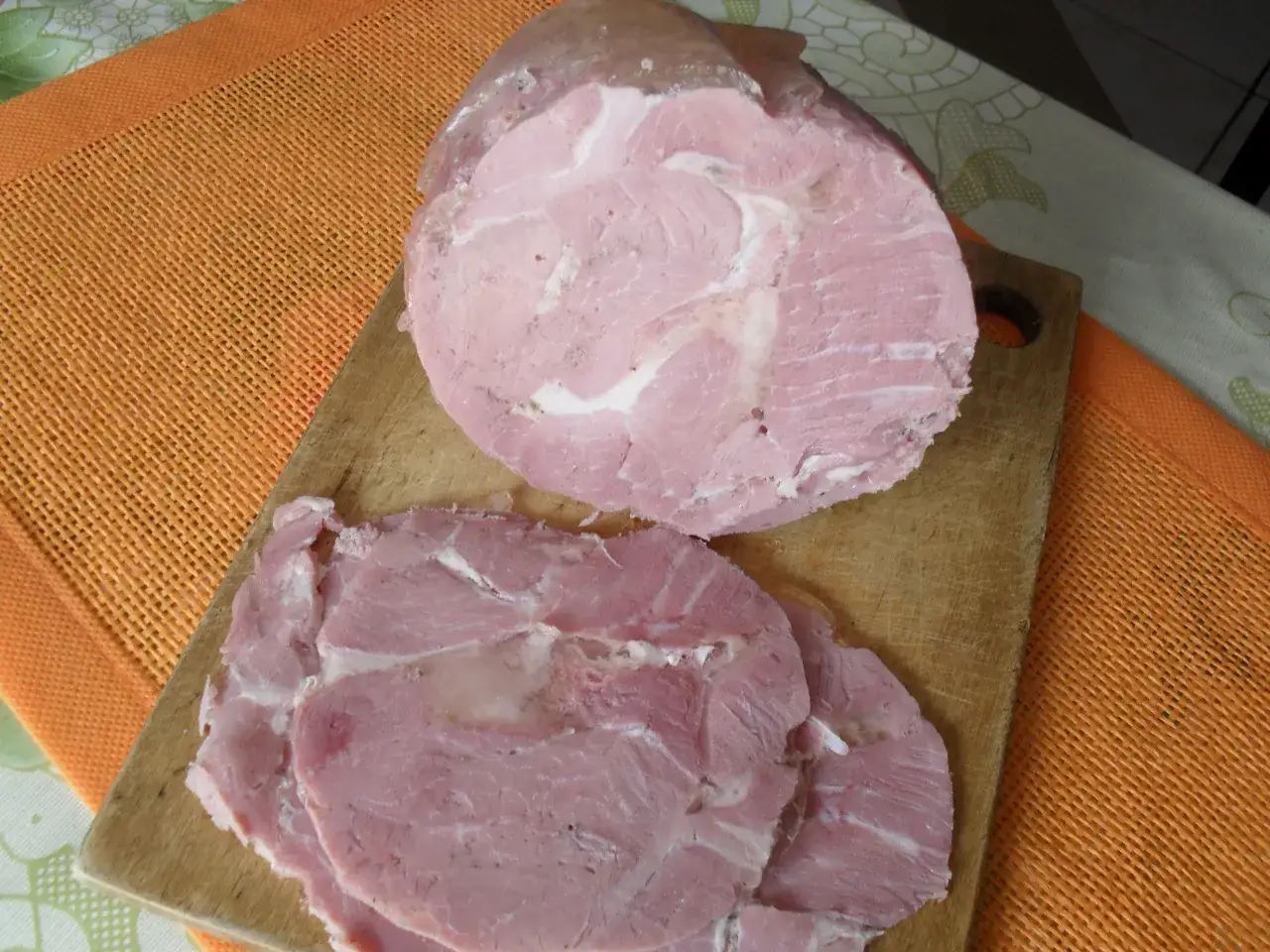 Pyszna kiełbasa z łopatki z szynkowara, pokrojona w plastry, leży na desce.