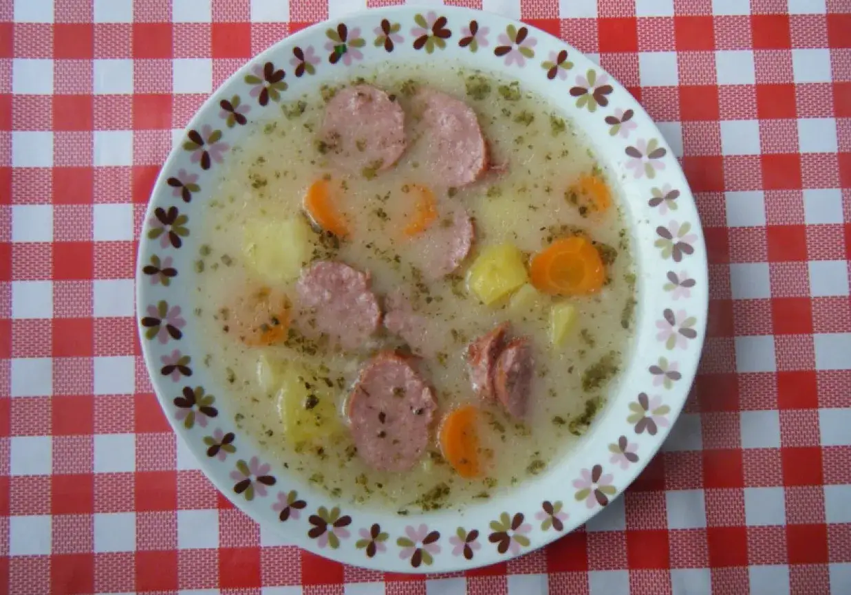 Talerz żurku z kiełbasą i ziemniakami na czerwono-białym obrusie. Zastanawiasz się, ile kcal ma żurek z kiełbasą i ziemniakami?