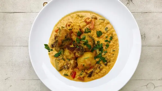 Pyszny ryż z curry z warzywami i kawałkami smażonego kurczaka, udekorowany natką pietruszki.