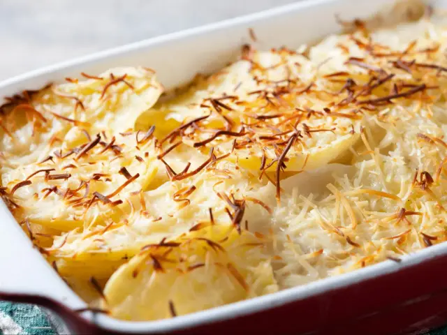 Zapiekanka ziemniaczana z serem, przypominająca danie raclette, w naczyniu żaroodpornym.
